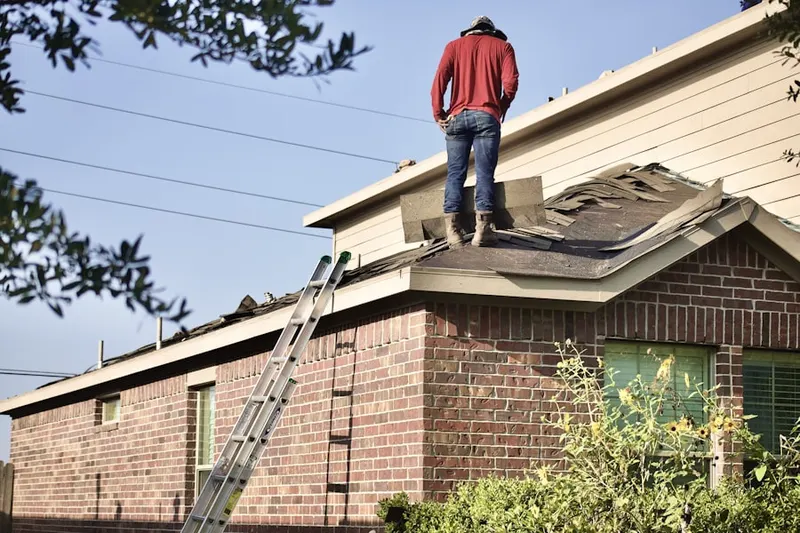 Professional roofer working on a residential roof in Gratigny Red